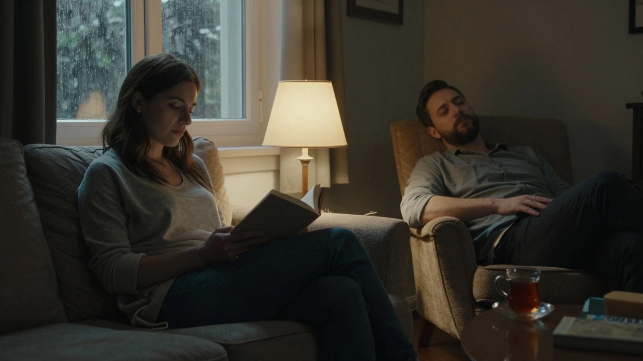 Yumuşak ışıkta, bir kadın kitap okurken bir erkek rahat koltukta sessizce oturuyor.